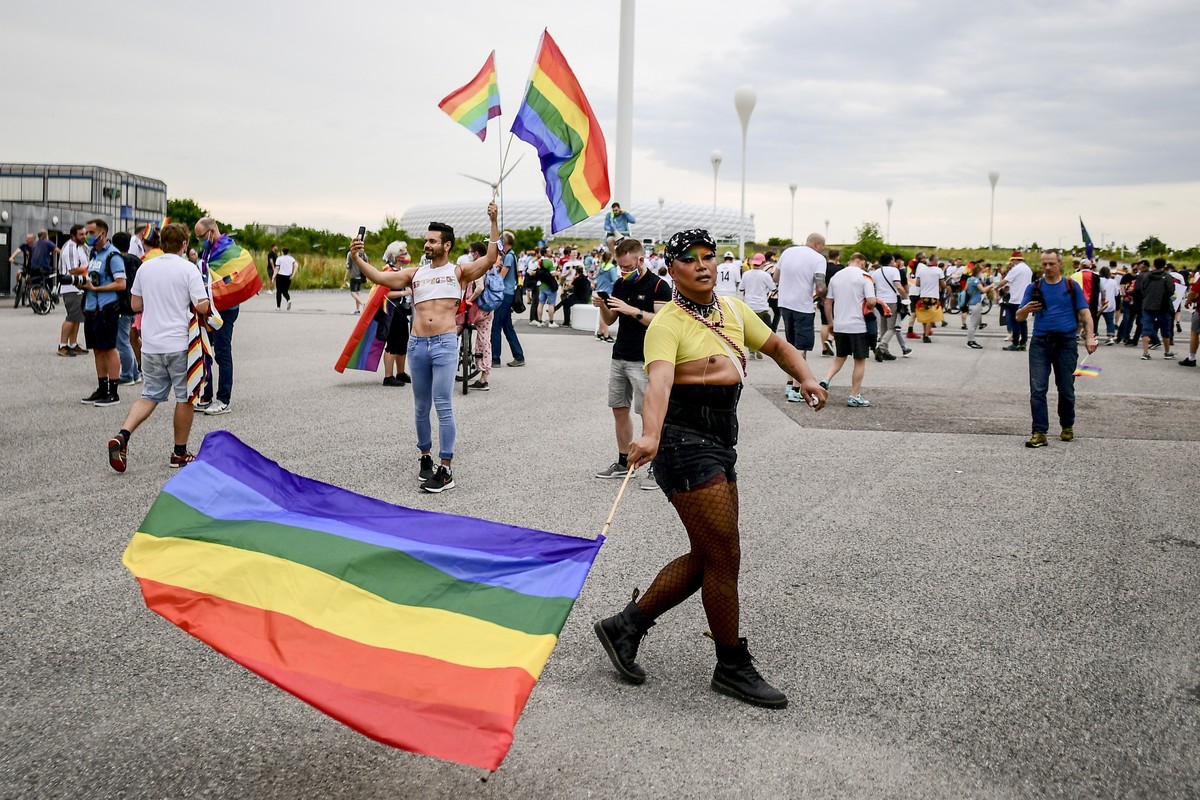 epa09296404 People wave rainbow flags in front of the Allianz Arena stadium in Munich, Germany, 23 June 2021. The UEFA on 22 June turned down a request by the city of Munich to illuminate the Allianz  ...