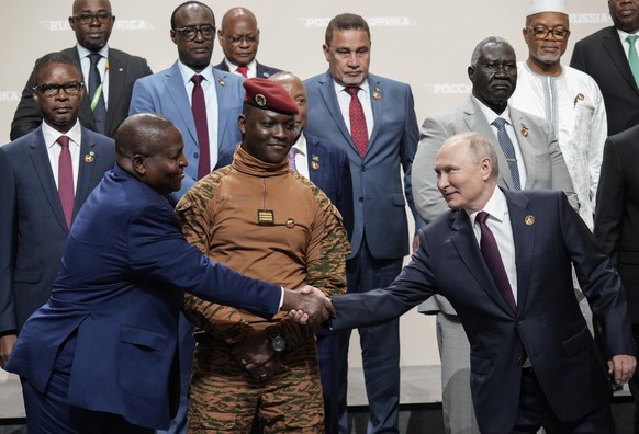 epa10773094 Russian President Vladimir Putin (R) shakes hands with Mozambique President Filipe Nyusi during a family photo with heads of delegations and participants of the Second Summit &#039;Russia- ...