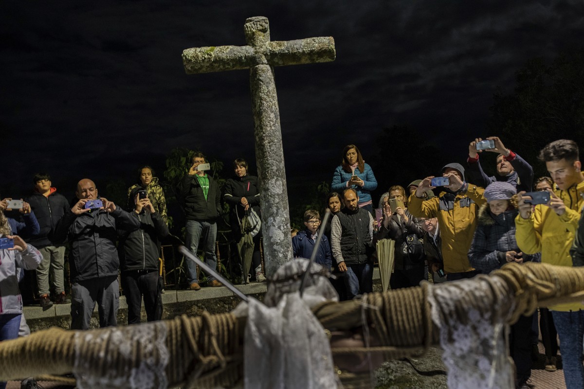 Villagers take snapshots of a penitent during the Catholic procession of 'Los Empalaos' in Valverde de la Vera, southwest Spain, early Friday, April 19, 2019. Hundreds of processions take pl ...