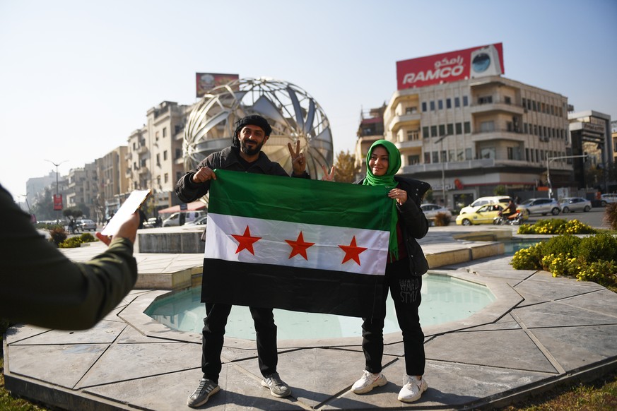 epa11766284 Syrians pose with the opposition flag on a street in Damascus, Syria, 09 December 2024. Syrian rebels entered Damascus on 08 December 2024 and announced in a televised statement the &#039; ...