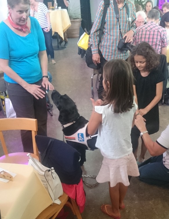 Eine Blinde und ihr Hund machen diesen beiden Kindern Freude.