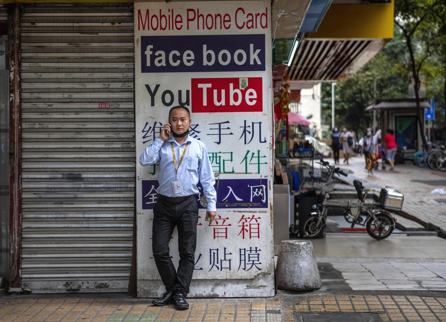 epa08421641 A man uses his phone in front of a store advertising Virtual Private Network (VPN) services and 'free internet' SIM cards allowing access to foreign websites that are restricted in China,  ...
