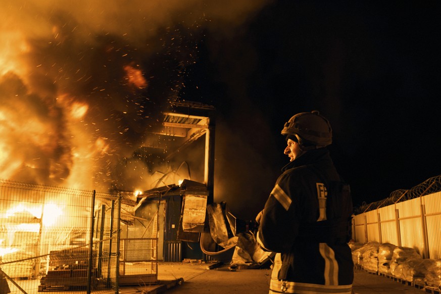 A Ukrainian State Emergency Service firefighter puts out a fire after Russian shelling hit a shopping center in Kherson, Ukraine, Friday, Feb. 3, 2023. (AP Photo/LIBKOS)