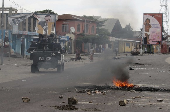 Policemen drive past burning debris during protests in Kinshasa, Democratic Republic of Congo, Tuesday, Dec. 20, 2016. Human Rights Watch says security forces have killed three people in Congo&#039;s  ...