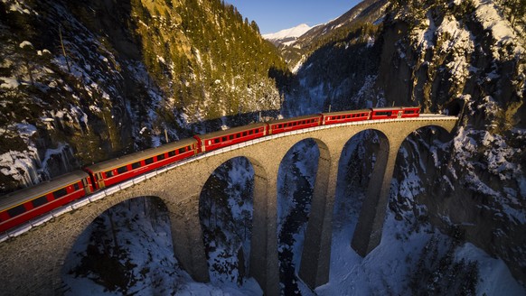 ARCHIVBILD ZUR BMK DER RHAETISCHEN BAHN, AM DONNERSTAG, 11. APRIL 2019 - A regional train from the Rhaetian Railway (RhB) passes on the iconic Landwasser viaduct during sunset, between Schmitten and F ...