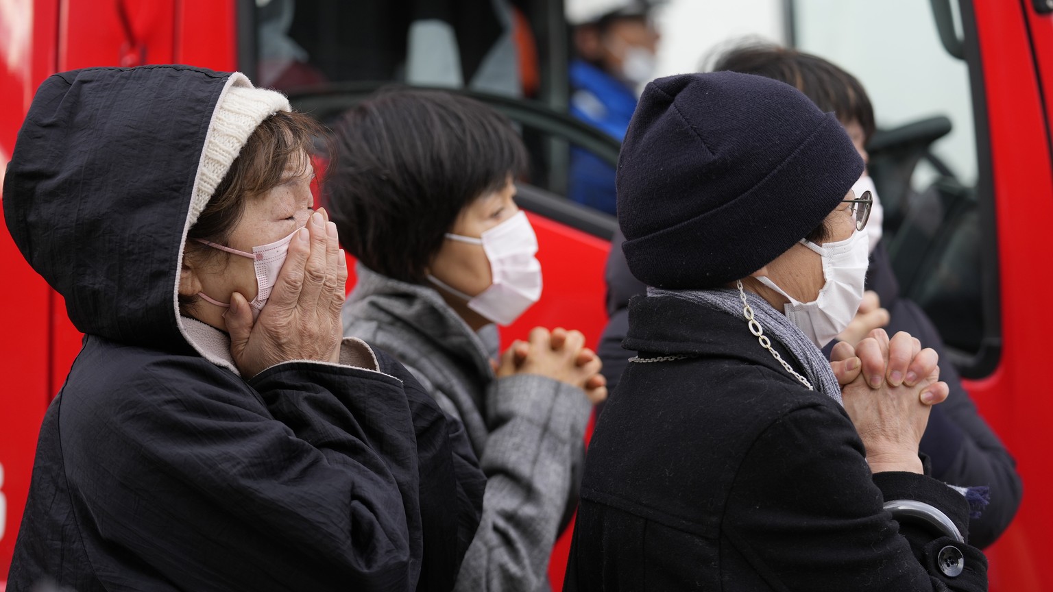 epa11057804 Local residents react as rescue workers carry out an operation at a collapsed house following an earthquake in Wajima, Ishikawa Prefecture, Japan, 05 January 2024. At least 82 people were  ...