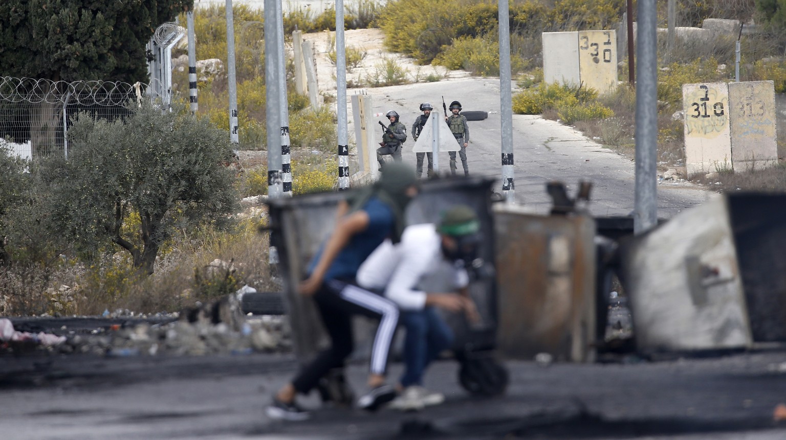 epa10929138 Palestinians (front) run for cover during clashes with Israeli troops at the northern entrance of the West Bank city of Ramallah, near the Israeli settlement of Beit El, 20 October 2023. A ...