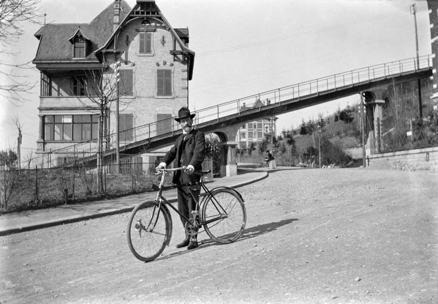Ein Mann mit Fahrrad vor einer Bruecke der Seilbahn Rigiblick in Zuerich, aufgenommen um 1901. (KEYSTONE/Str)