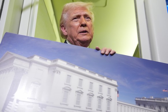 President Donald Trump holds a rendering of the proposed new East Wing of the White House as he speaks to reporters aboard Air Force One en route from West Palm Beach, Fla., to Joint Base Andrews, Md. ...
