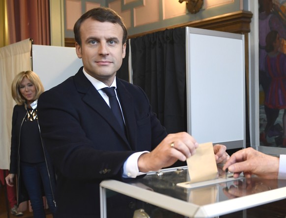 French presidential election candidate for the En Marche ! movement Emmanuel Macron casts his ballot while his wife Brigitte Macron looks on, at a polling station in Le Touquet, northern France, durin ...