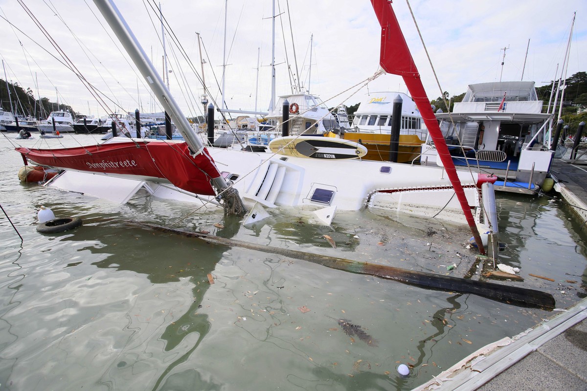 A damaged boat is partially submerged in a marina at Tutukaka, New Zealand, Sunday, Jan. 16, 2022, after waves from a volcano eruption swept into the marina. An undersea volcano erupted in spectacular ...