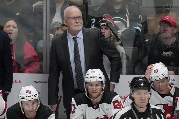 New Jersey Devils coach Lindy Ruff, standing, watches from the bench during the third period of the team&#039;s NHL hockey game against the San Jose Sharks in San Jose, Calif., Tuesday, Feb. 27, 2024. ...