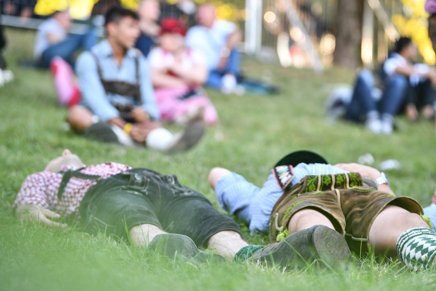 epa07859643 Visitors rest on a meadow during the opening day of the 186th Oktoberfest beer festival on the Theresienwiese in Munich, Germany, 21 September 2019. The Munich Beer Festival is the world&# ...