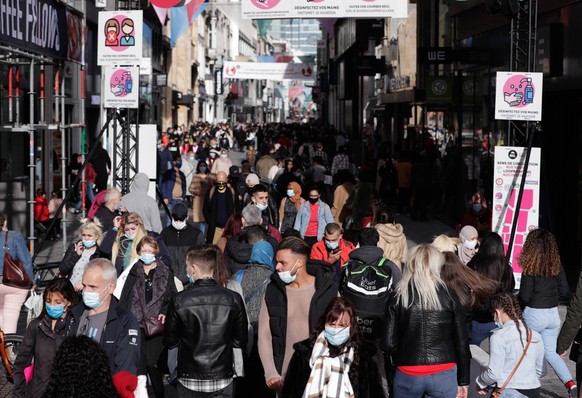 epa08788714 People queue in front of so-called non-essential stores 2 days before new measures against COVID-19 come into force in Rue Neuve, the main shopping street in Brussels, Belgium, 31 October  ...