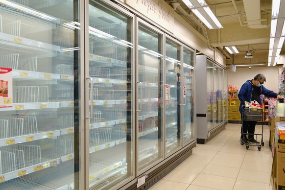 A man wearing a face mask walks past empty shelves of frozen food as residents concerned with possible supply shortages stock up on food at a supermarket in Hong Kong, Tuesday, March 8, 2022. The fast ...