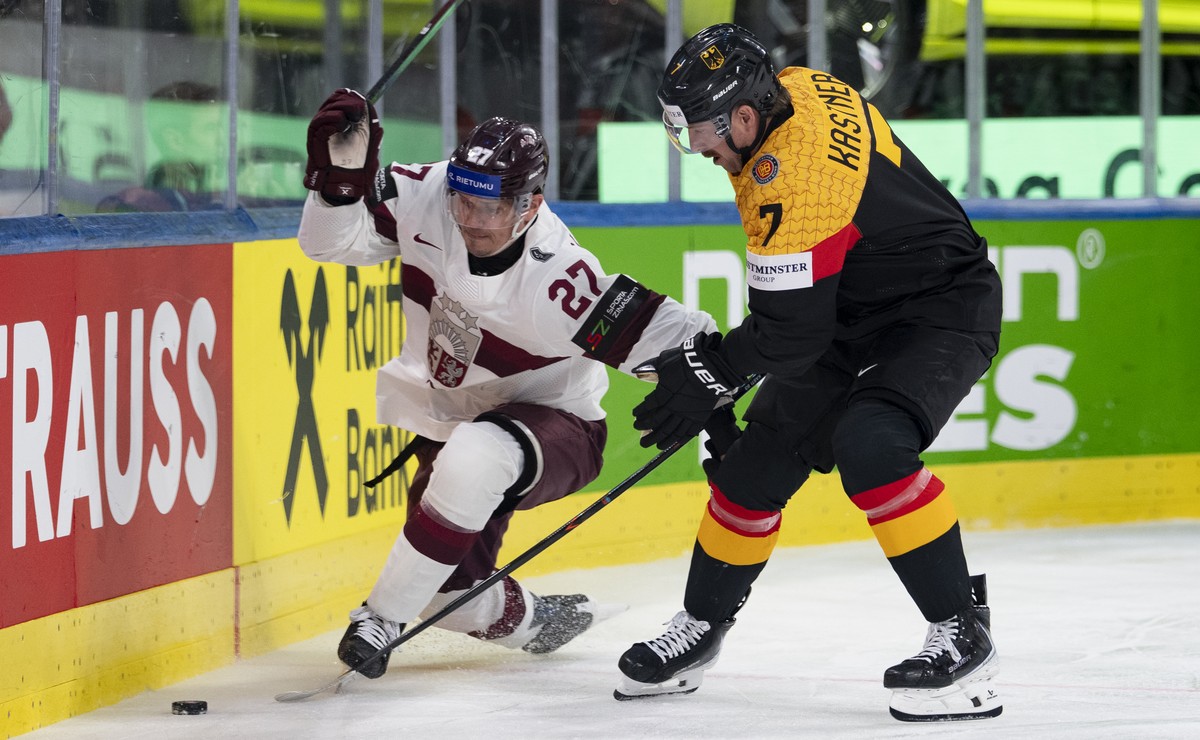 Latvia's Oskars Cibulskis, left, fights for the puck against Germany's Maximilian Kastner, right, during the 2026 IIHF Men's Ice Hockey World Championship preliminary round group A game ...
