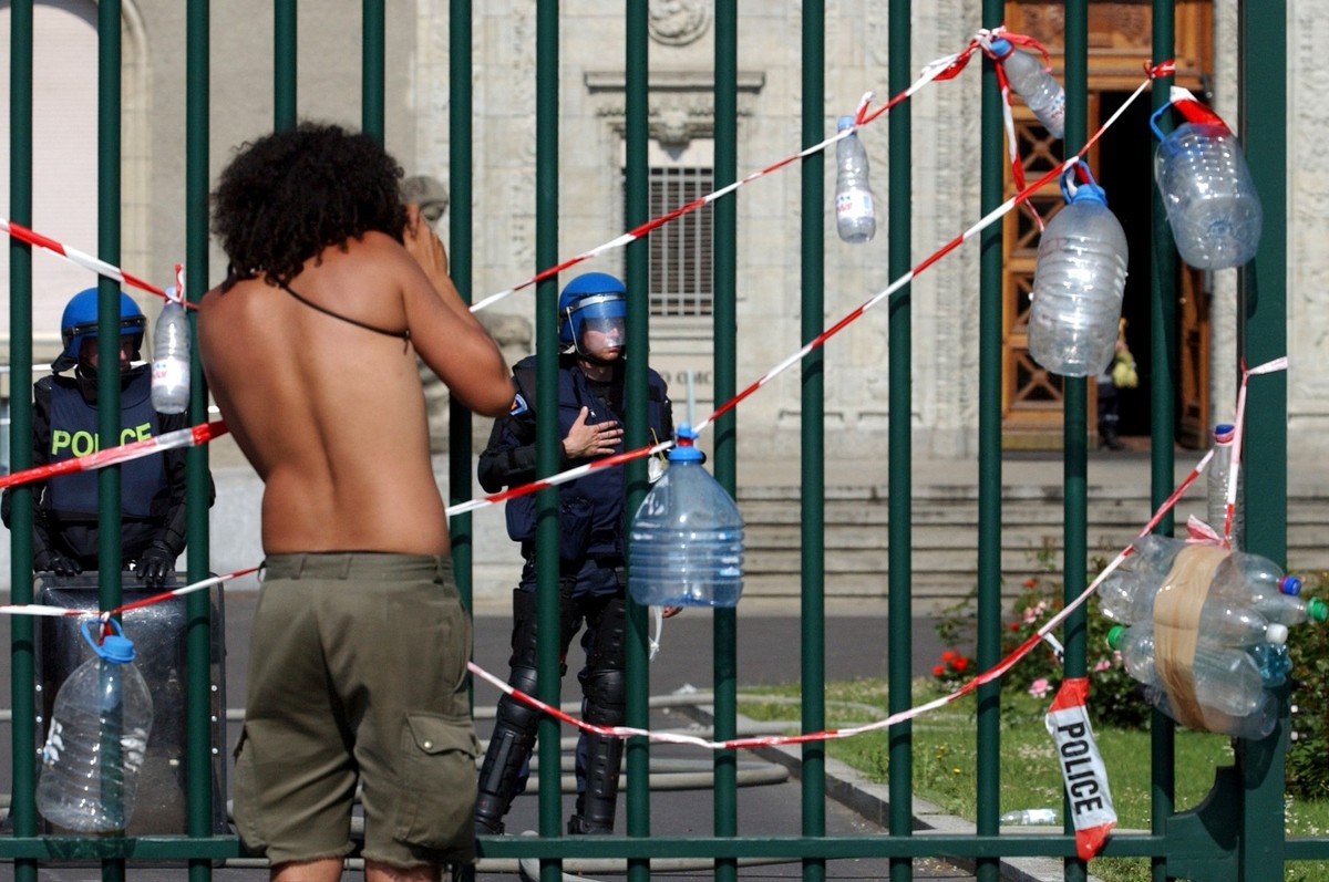 A anti-G8 demonstrator stands in front of the well watched iron bars of the World Trade Organization (WTO) building in Geneva, Switzerland, Monday, June 2, 2003, in a protest for free water for everyo ...