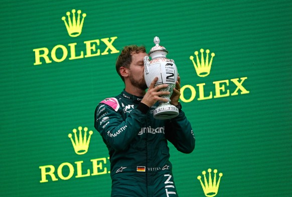 epa09386114 German Formula One driver Sebastian Vettel of the Aston Martin Cognizant F1 Team kisses his trophy on the podium after taking the second place in the Formula One Grand Prix of Hungary at t ...