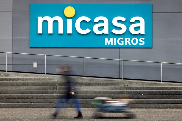 KEYPIX - Eine Frau geht mit einem Wagen neben einem Logo einer Micasa Filiale vorbei, aufgenommen am Dienstag, 25. Februar 2025 in Duebendorf. Die Migros setzt ihre Konzentration aufs Kerngeschaeft fo ...