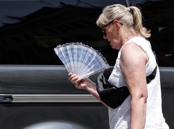 epa10751447 A woman uses a fan amid high temperatures, in Rome, Italy, 17 July 2023. Southern Europe is experiencing a major heat wave this week with temperatures expected to climb up to 48 Celsius de ...