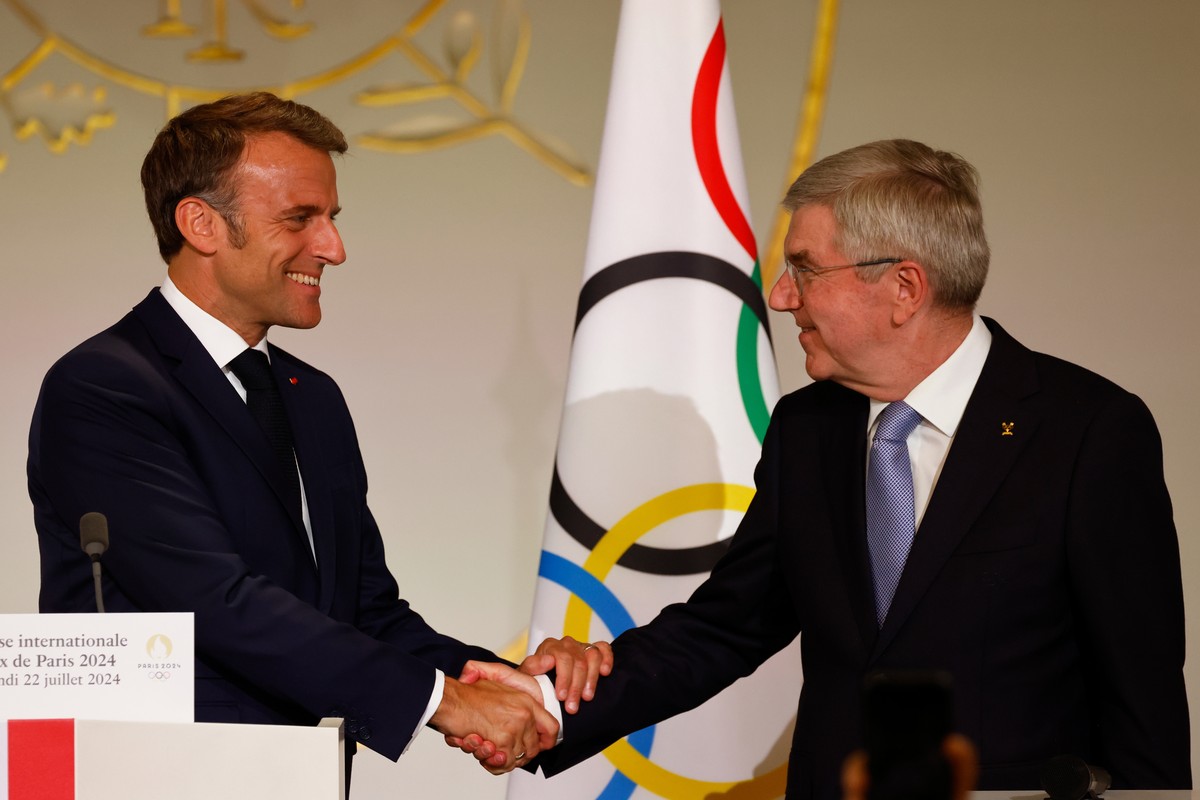 epa11491628 France's President Emmanuel Macron (L) shakes hands with International Olympic Committee (IOC) President Thomas Bach (R), during a reception for international journalists accredited f ...