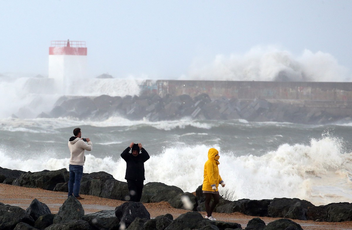 People walk near the sea in Anglet, southwestern France, Sunday, Nov. 3, 2019. Most of the French regions are on alert for violent storms and high winds. (AP Photo/Bob Edme)