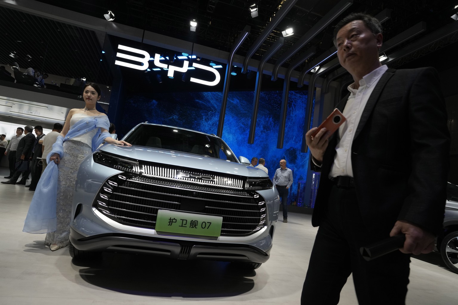 FILE - A model stands next to a car from BYD during the Shanghai auto show in Shanghai, on April 18, 2023. BYD Co., based in the southern China tech hub of Shenzhen, dethroned Texas-based Tesla Inc. a ...