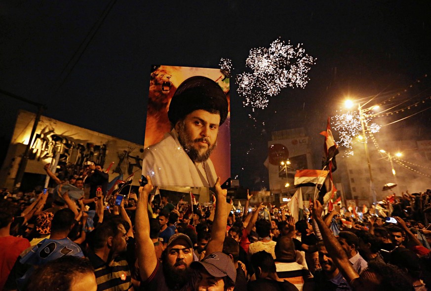 FILE - In this Monday, May 14, 2018 file photo, supporters of Shiite cleric Muqtada al-Sadr, carry his image as they celebrate in Tahrir Square, Baghdad, Iraq. Al-Sadr, who led punishing attacks on Am ...