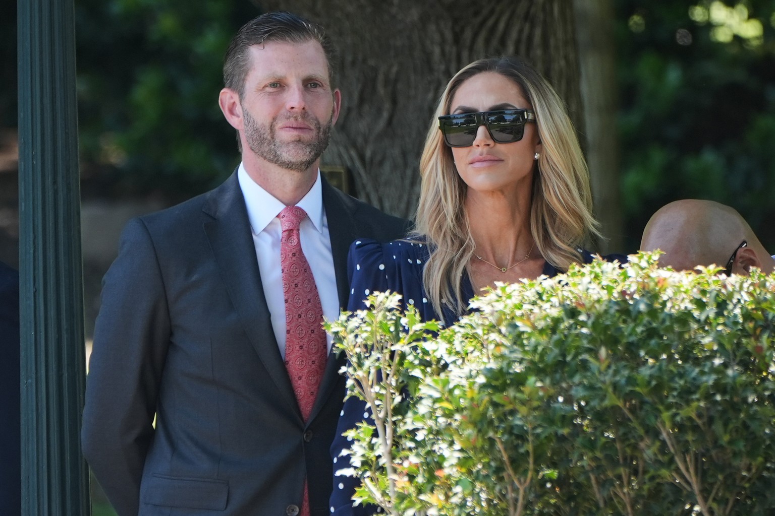 Eric and Lara Trump watch as President Donald Trump talks with reporters as he departs the White House for travel to Beijing, Tuesday, May 12, 2026, in Washington, to meet with China's President  ...