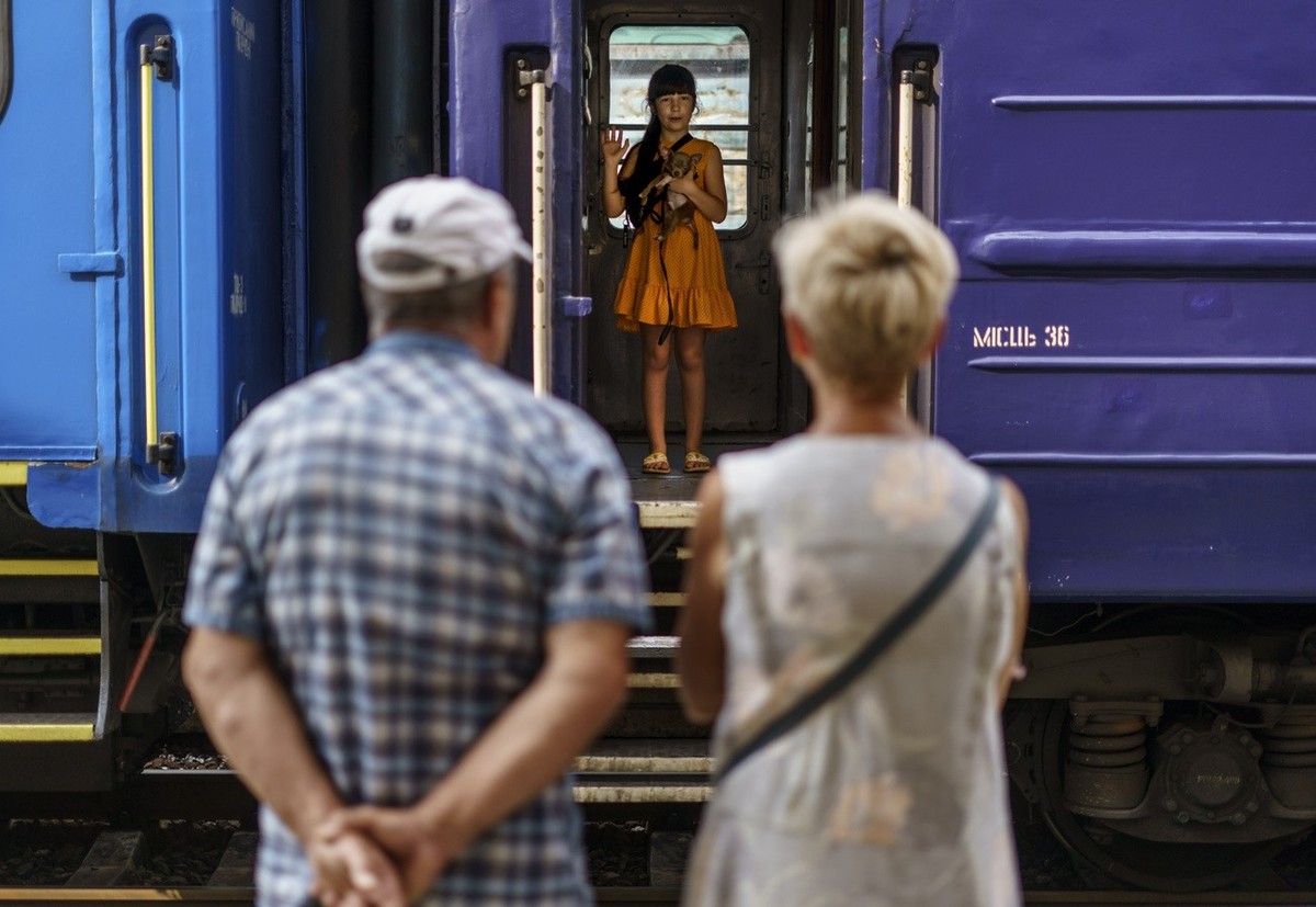 A young girl holds her dog while waving goodbye to her grandparents from an evacuation train departing Pokrovsk, Donetsk region, eastern Ukraine, Tuesday, Aug. 2, 2022, for a safer part of the country ...