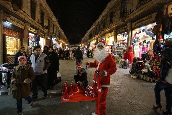 epa06405006 A Syrian is dressed in Santa Claus clothes is seen at al-Hamidiyeh old souk in Damascus, Syria, 24 December 2017. Prior to the current conflict, Christians are believed to have made around ...