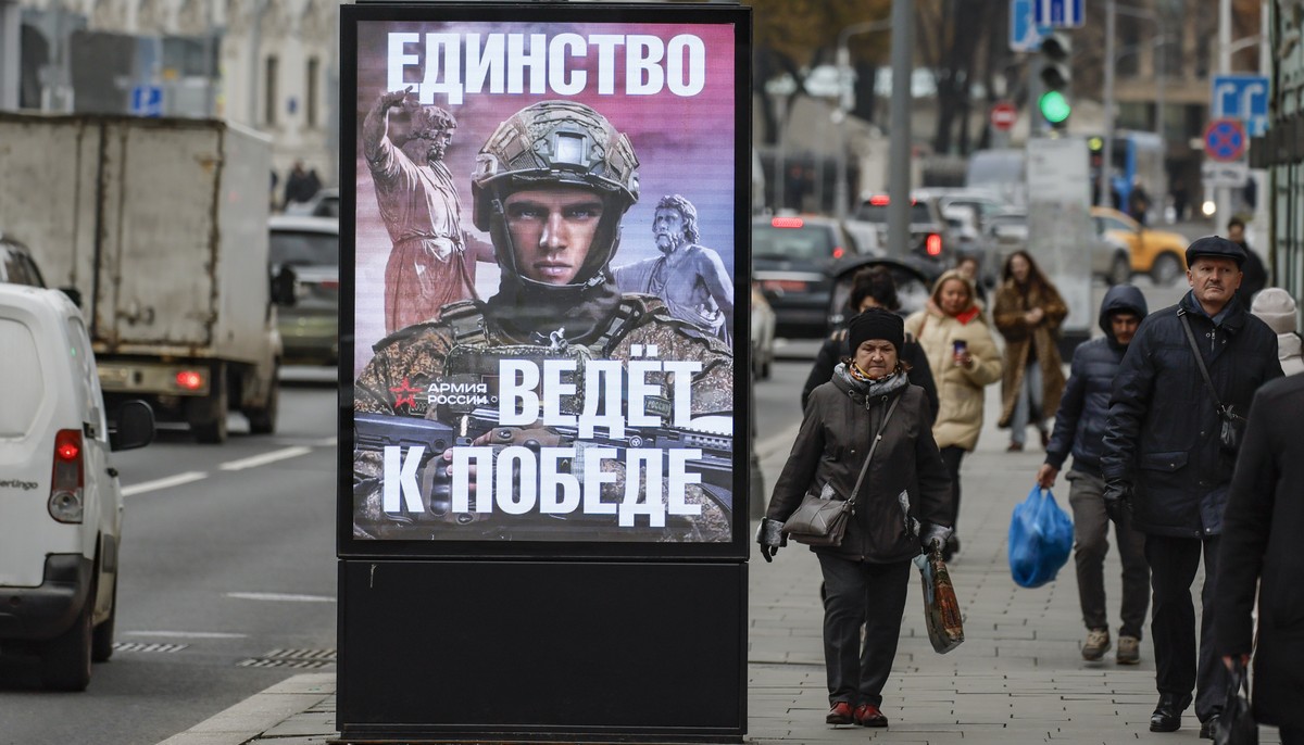 epa11720654 People walk past an electronic screen with an image depicting Russian soldier and the slogan 'Unity leads to victory' in downtown Moscow, Russia, 14 November 2024. About 190,000  ...
