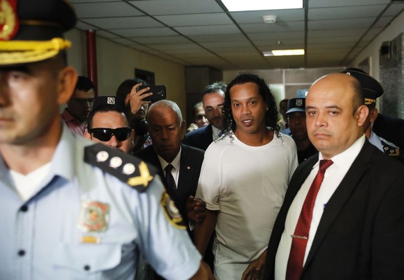 Former soccer star Ronaldinho, center, is escorted by police to go before Judge Mirko Valinotti at the Justice Palace court in Asuncion, Paraguay, Friday, March 6, 2020. Ronaldinho has been detained b ...