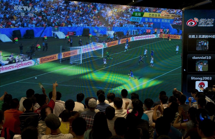 Chinese soccer fans watching the 2014 World Cup final match between Germany and Argentina, being played in Brazil, on a TV screen in Beijing, China Monday, July 14, 2014. (AP Photo/Andy Wong)