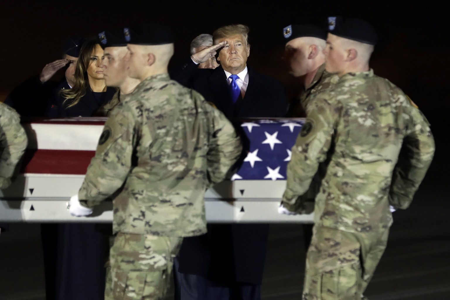 President Donald Trump and first lady Melania Trump watch as a U.S. Army carry team moves a transfer case containing the remains of Chief Warrant Officer 2 David C. Knadle, of Tarrant, Texas, Thursday ...