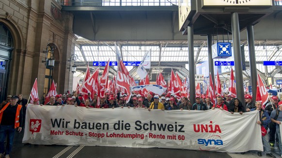 Mitglieder der Gewerkschaft Unia demonstrieren am Zuerich Hauptbahnhof neben der Bahnhofsuhr am Dienstag, 10. November 2015, bezueglich der erneuerung des Landesmantelvertrags. Ueber hundert Baustelle ...