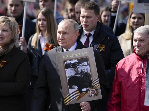 Russian President Vladimir Putin, center, attends the Immortal Regiment march through Red Square marking the 77th anniversary of the end of World War II, in Moscow, Russia, Monday, May 9, 2022. (AP Ph ...