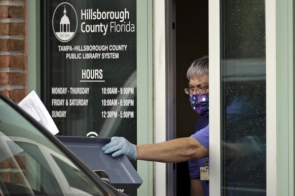 Hillsborough County Library Service employee Stephen Duran wears a mask and gloves to protect himself from the coronavirus outbreak as he hands out unemployment paperwork to residents Tuesday, April 1 ...