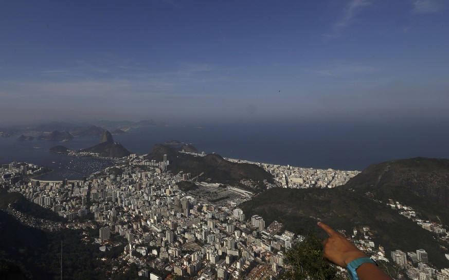 A tourist points towards the city while visiting the Christ the Redeemer statue in Rio de Janeiro, Brazil August 6, 2016. REUTERS/Leonhard Foeger