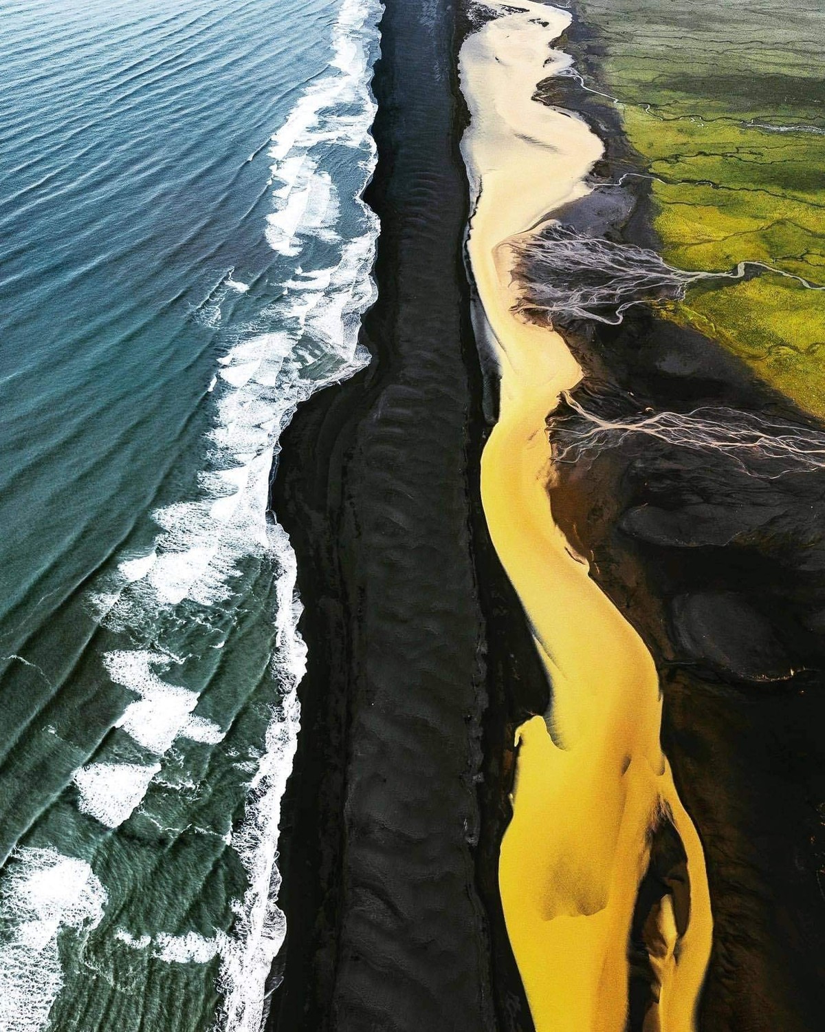 There's a place in Iceland where green fields, a yellow river, a black beach and the ocean meet.