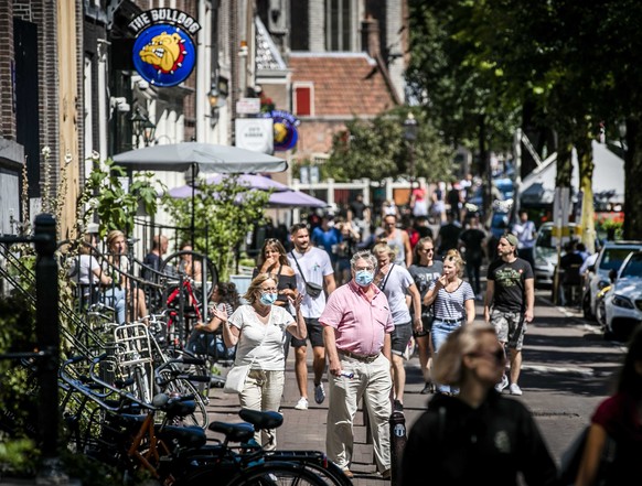 epa08585202 People wearing face masks walk on the Red Light District in Amsterdam, The Netherlands, 05 August 2020. From today, wearing a face mask is mandatory in five usually crowded places in the c ...