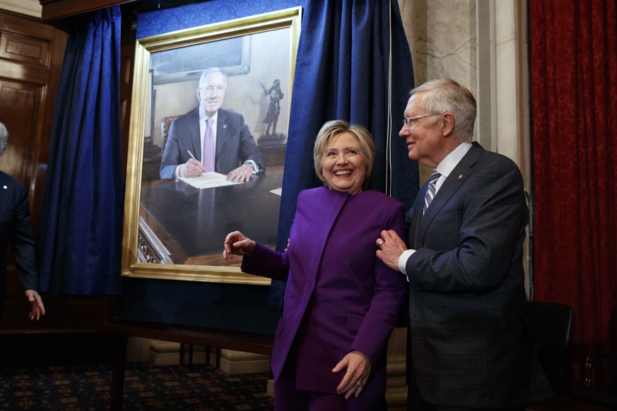 Former Secretary of State Hillary Clinton, left, smiles as Senate Minority Leader Sen. Harry Reid, D-Nev., poses her for a photograph during a ceremony to unveil a portrait of Reid, on Capitol Hill, T ...