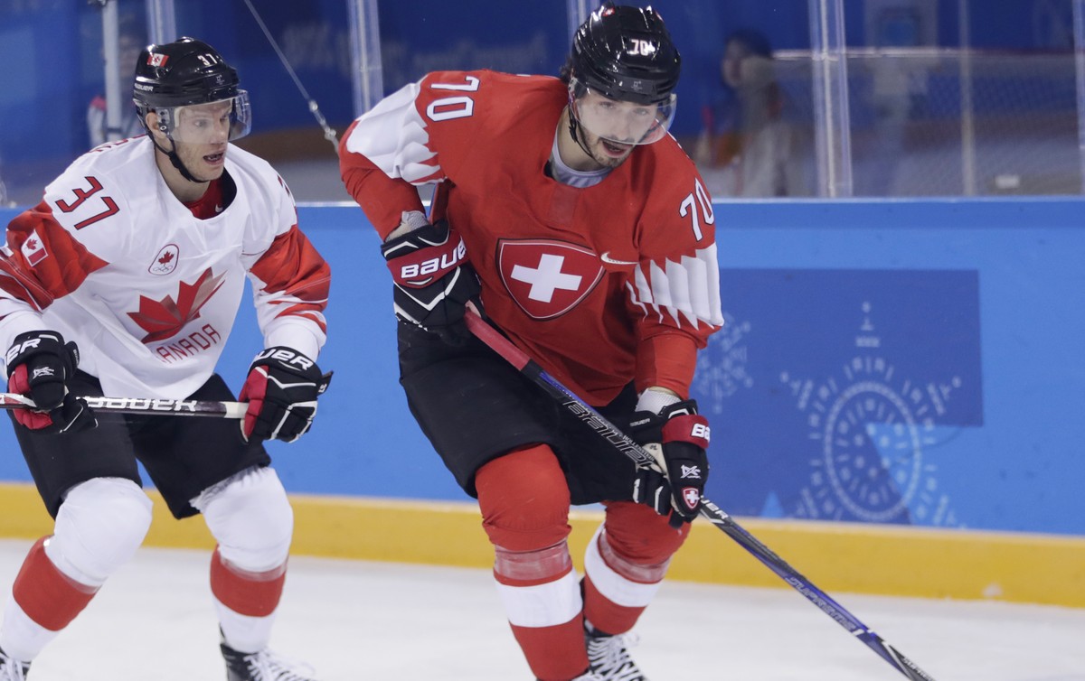 Denis Hollenstein (70), of Switzerland, skates with the puck against Mat Robinson (37), of Canada, during the first period of a preliminary round men's hockey game at the 2018 Winter Olympics in  ...