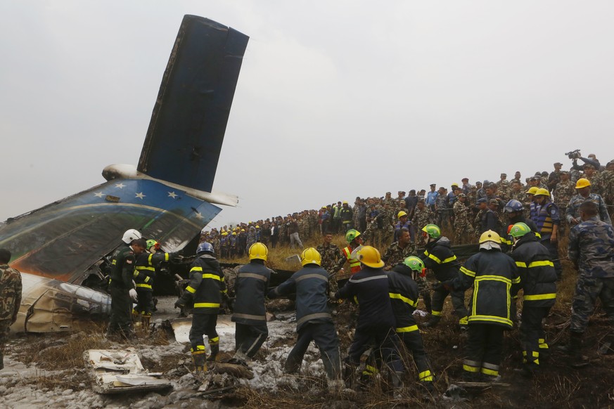 Nepalese rescuers work amid the debris after a passenger plane from Bangladesh crashed at the airport in Kathmandu, Nepal, Monday, March 12, 2018. The passenger plane carrying 71 people from Banglades ...