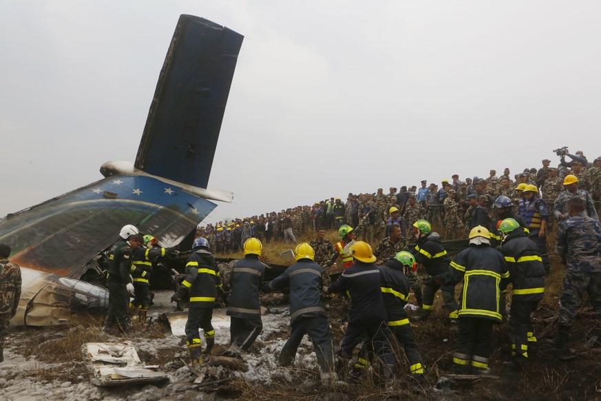 Nepalese rescuers work amid the debris after a passenger plane from Bangladesh crashed at the airport in Kathmandu, Nepal, Monday, March 12, 2018. The passenger plane carrying 71 people from Banglades ...