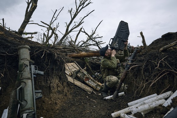 A Ukrainian soldier uses an anti-drone gun against a Russian drone as he sits in a trench near Avdiivka, in the Donetsk region, Ukraine, Friday, April 28, 2023. (AP Photo/Libkos)