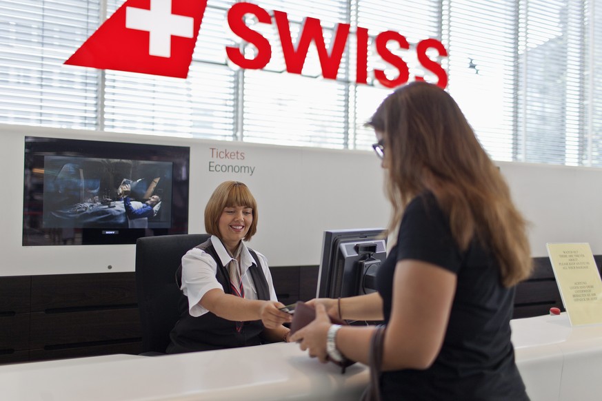 ZU DEN GESCHAEFTSZAHLEN 2013 DER FLUGGESELLSCHAFT SWISS STELLEN WIR IHNEN FOLGENDES THEMENBILD ZUR VERFUEGUNG - Eine Kundin kauft bei der Fluggesellschaft swiss am Flughafen in Zuerich ein Flugticket, ...