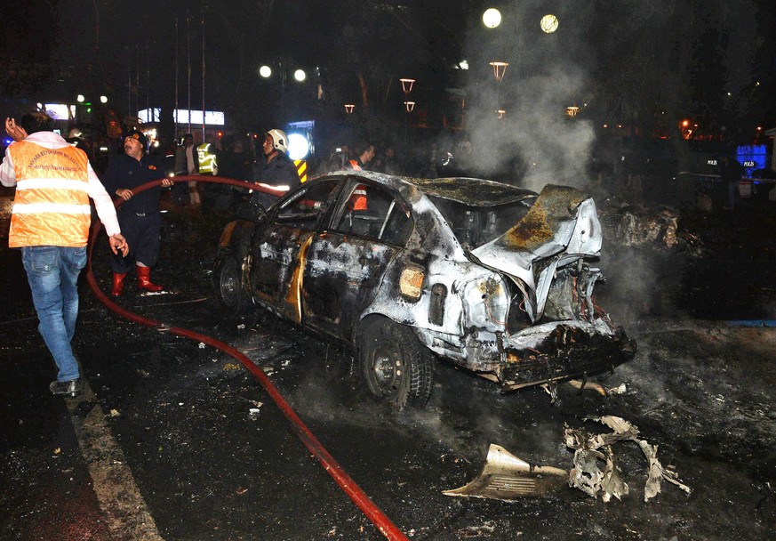 Feuerwehrleute löschen ein brennendes Auto.