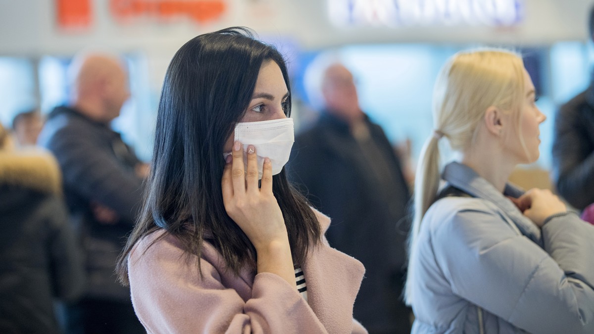 epa08246746 A woman wearing a protective mask is waiting for arriving passengers at airport of Chisinau, Moldova, 25 February 2020. Moldova's government decided to increase border crossing contro ...