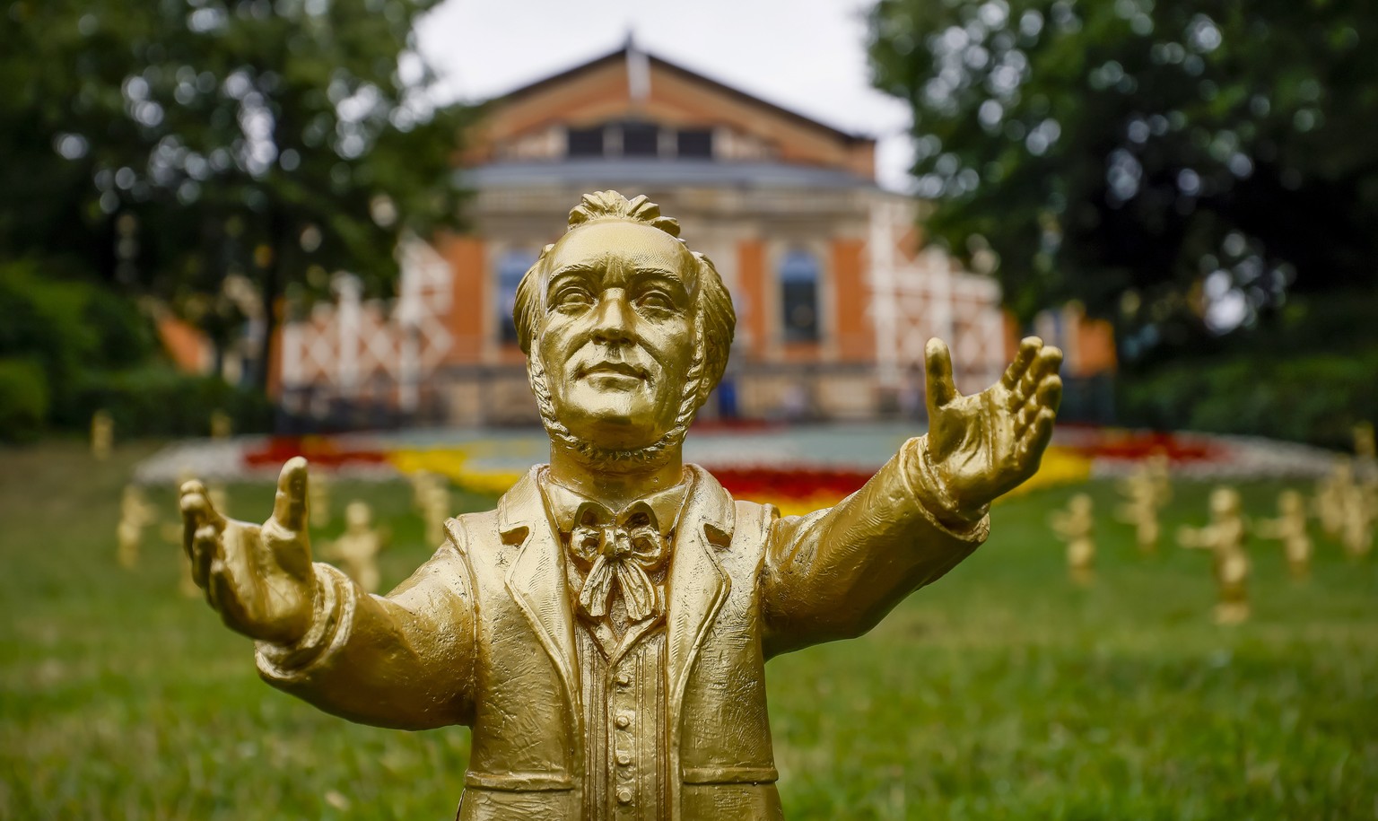 epa10767303 Wagner sculptures by the German artist Ottmar Hoerl stand on the lawn in front of the 19th century Bayreuth Festival Opera House before the opening of the 112th Bayreuth Opera Festival (Fe ...